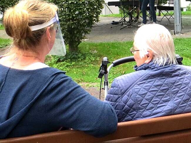 Eine Mitarbeiterin vom Kurhaus am Park unterhält sich mit einer Seniorin.