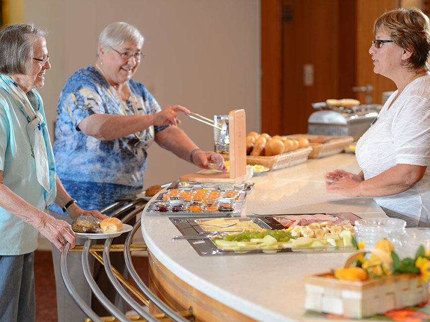 Zwei Seniorinnen im Kurhaus holen sich Essen am Buffet. 